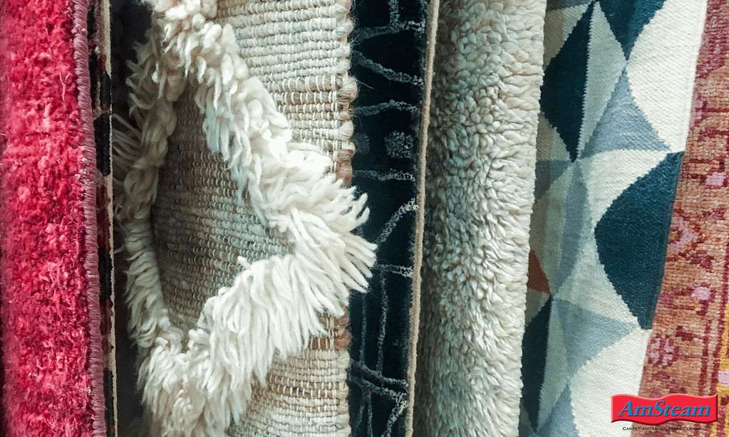 Multiple area rugs of different piles, textures and fibre types hanging  in a show room